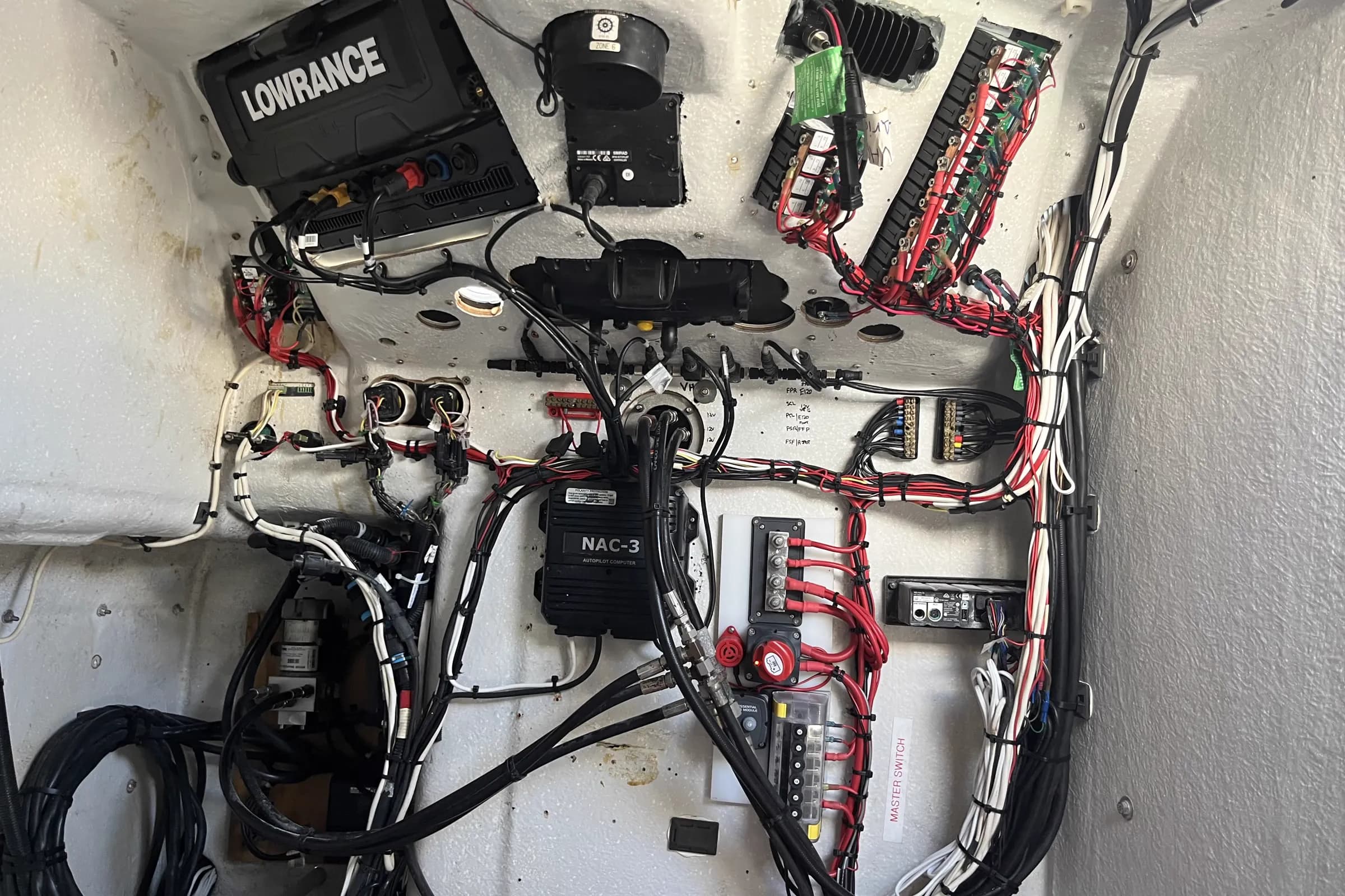 The same boat console cavity after rewiring, with the loom clipped to the hull in straight runs, a new breaker panel, busbars and the NAC-3 autopilot computer clear