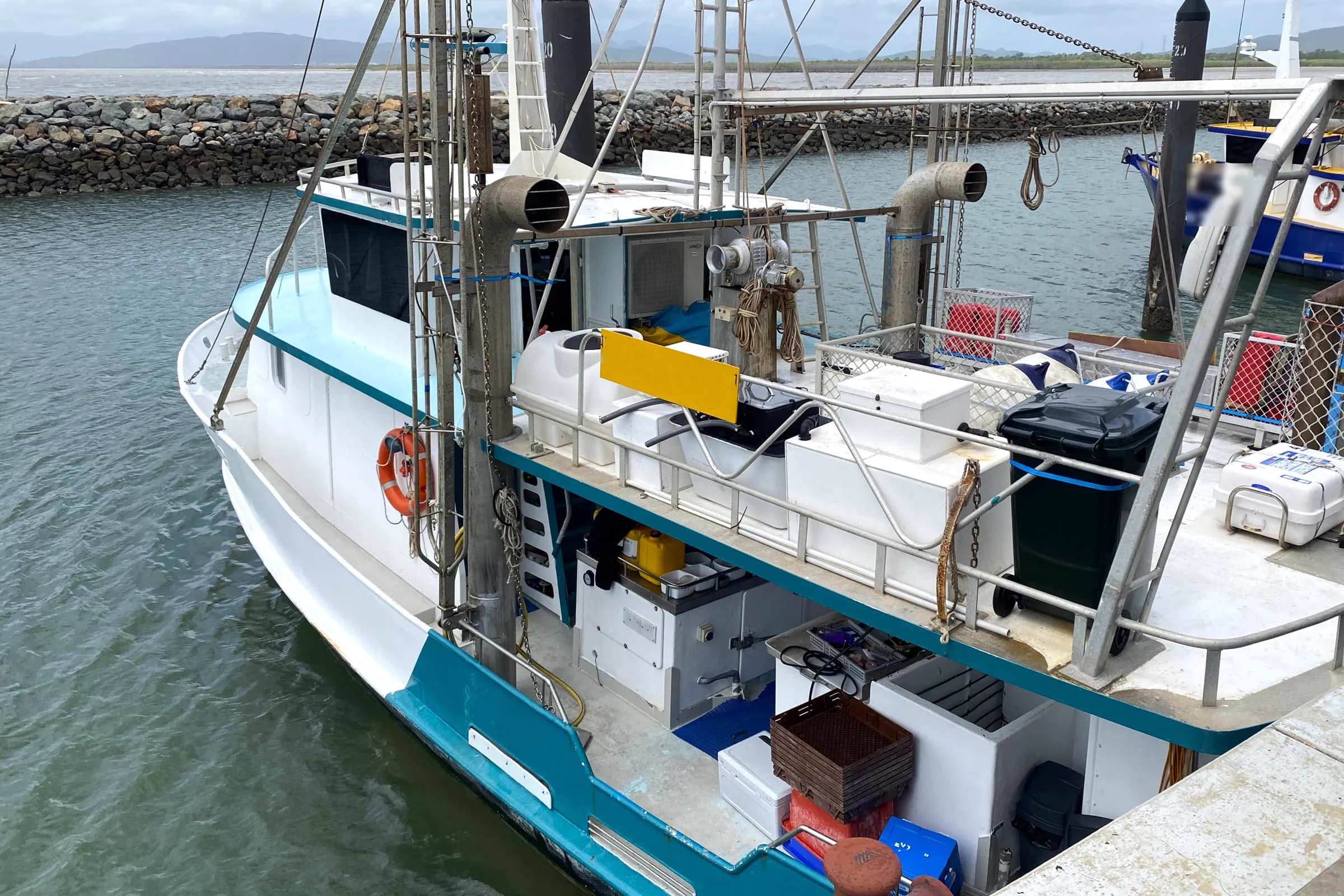 A commercial fishing trawler moored alongside a wharf in North Queensland with its deck gear and crates aboard