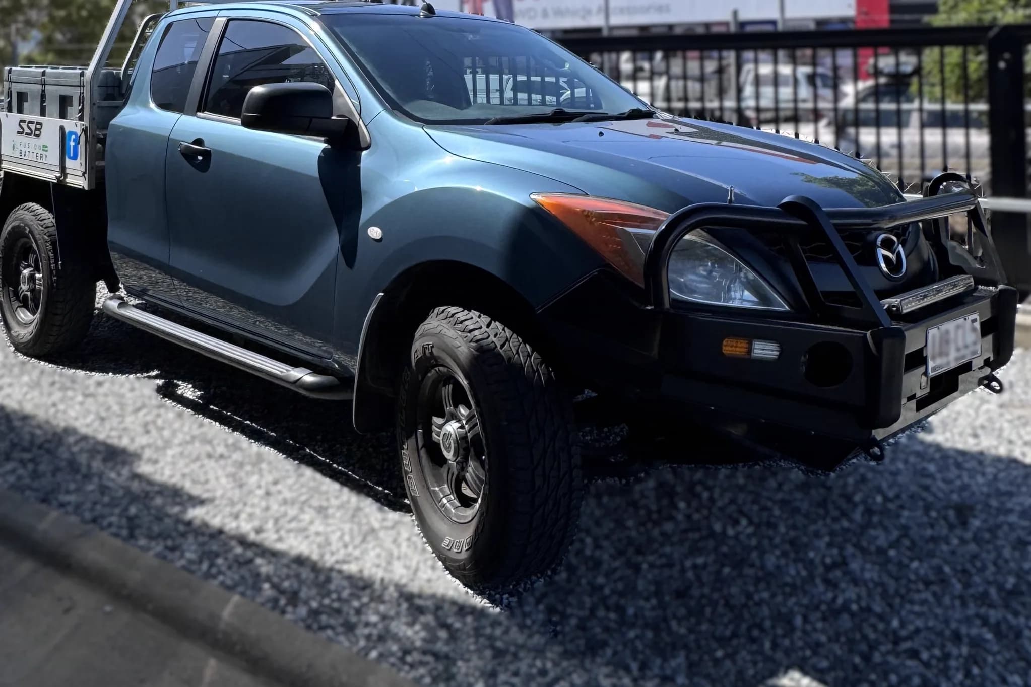 A blue Mazda BT-50 space cab work ute with a bullbar and an alloy tray, carrying Townlec Auto Electrical signage