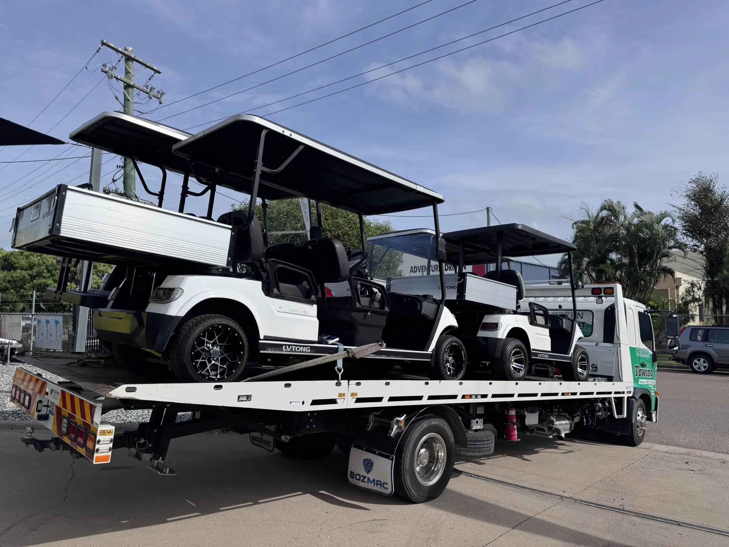 Four white LVTong utility carts loaded onto a tilt-tray truck outside the Townlec workshop, going out on hire