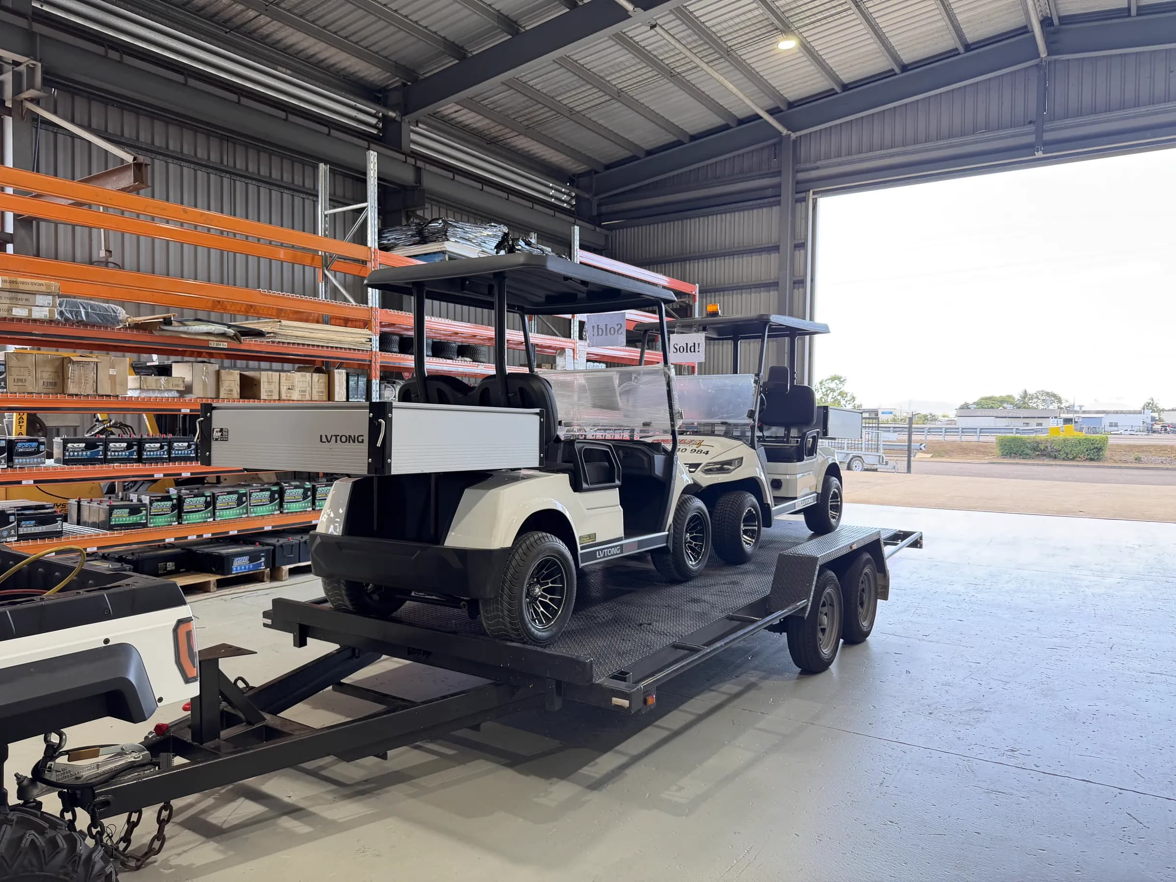 Two sold LVTong carts loaded on a trailer inside the Townlec workshop, with SSB battery racking behind them