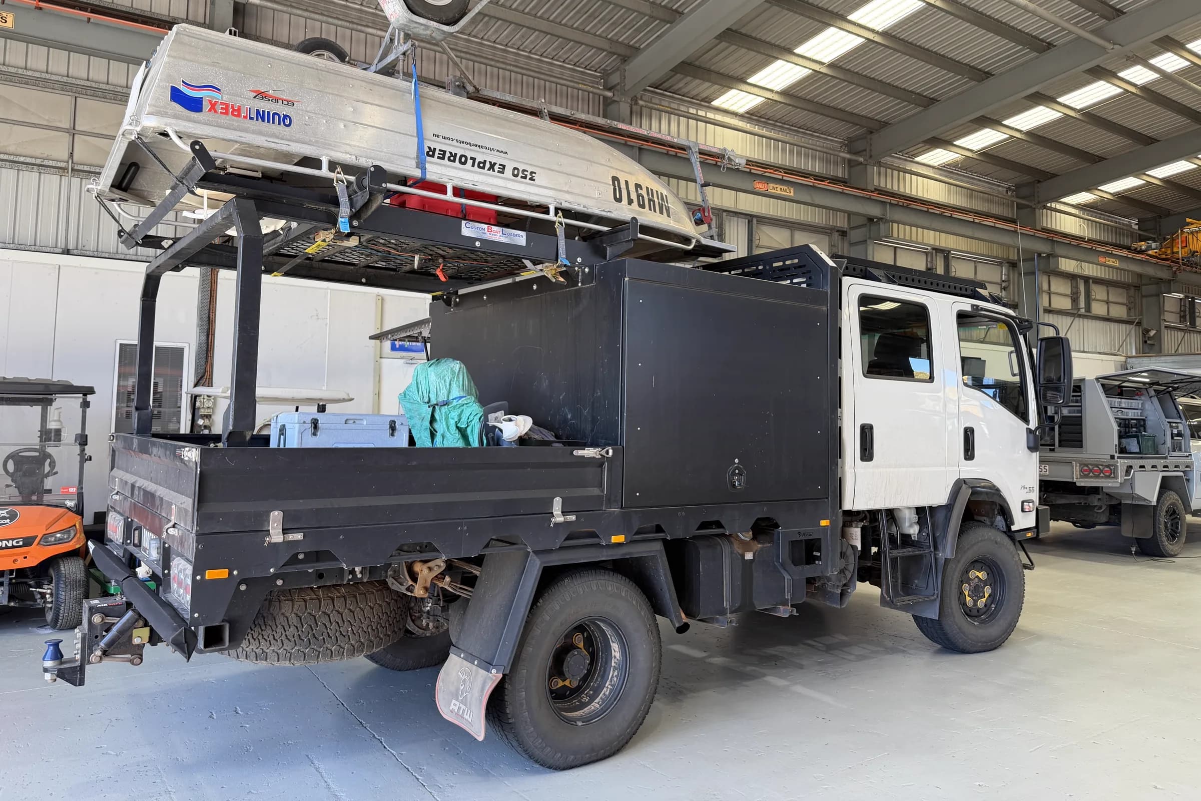 The rear of the Isuzu 4x4 with a Quintrex dinghy loaded upside down on a boat loader rack above the canopy