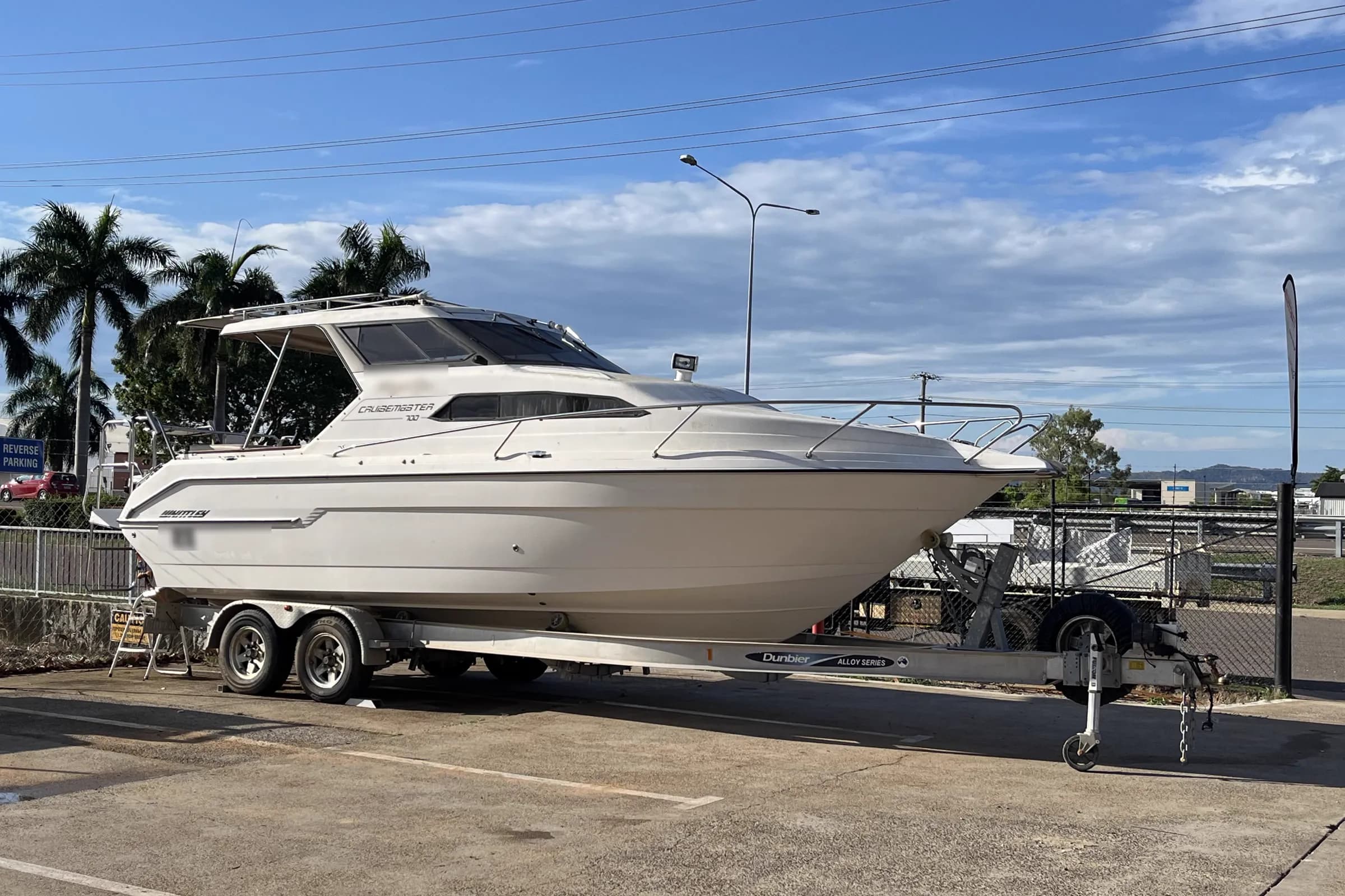 A Whittley Cruisemaster 700 cabin boat sitting on a tandem Dunbier alloy trailer