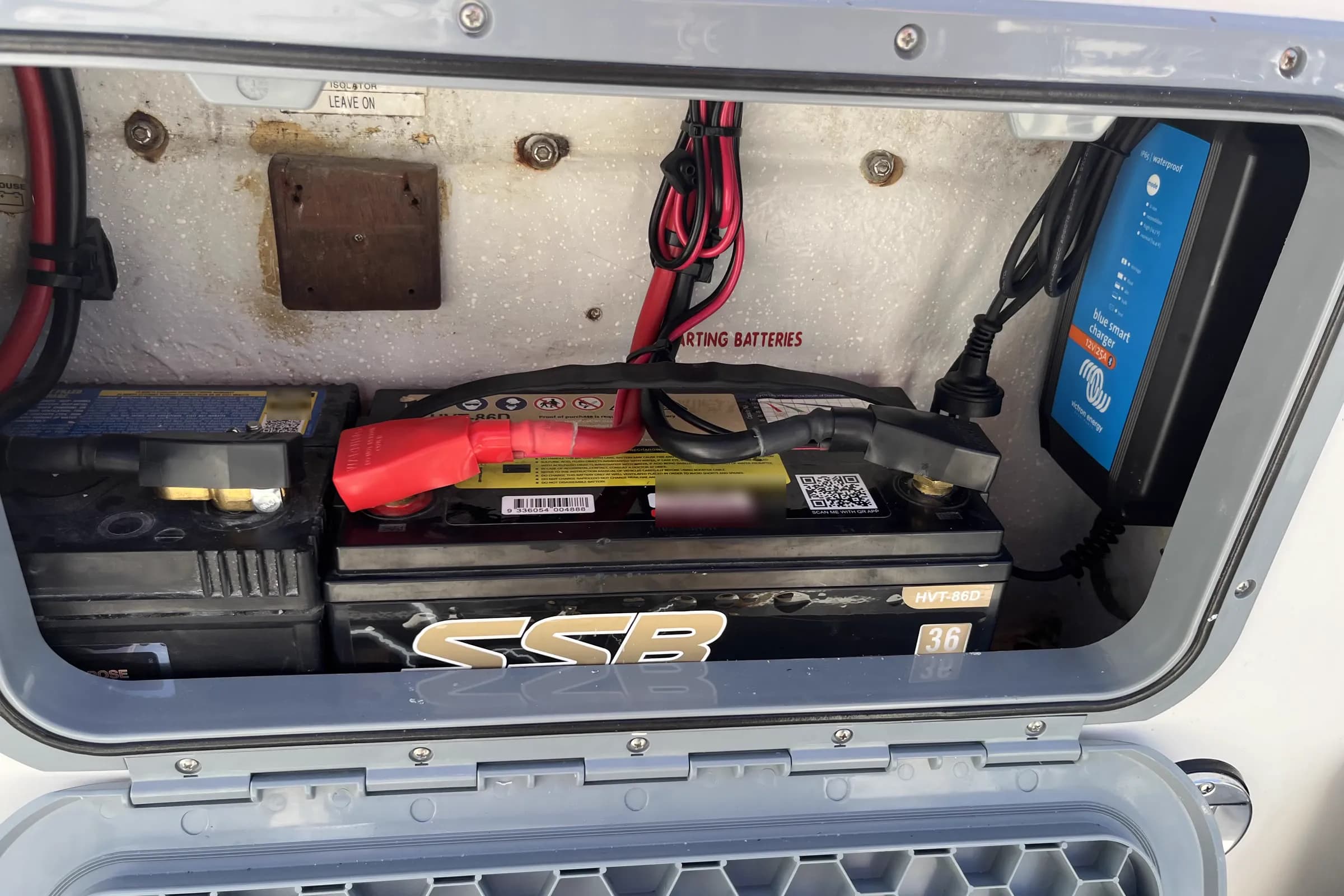 A boat battery locker with two SSB HVT-86D batteries and a Victron Blue Smart charger wired in above them